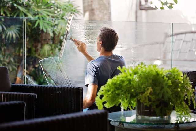 person cleaning glass separator in office space