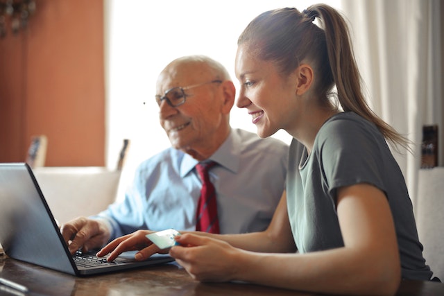 two people on a computer holding a credit card