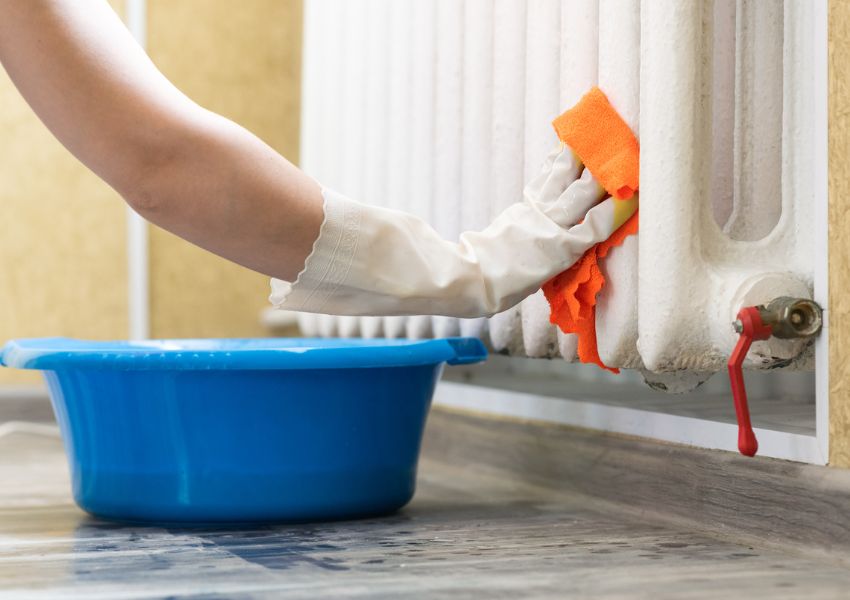 person-cleaning-radiator-with-cloth