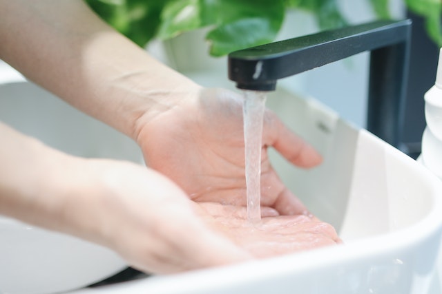 person washing hands under running faucet