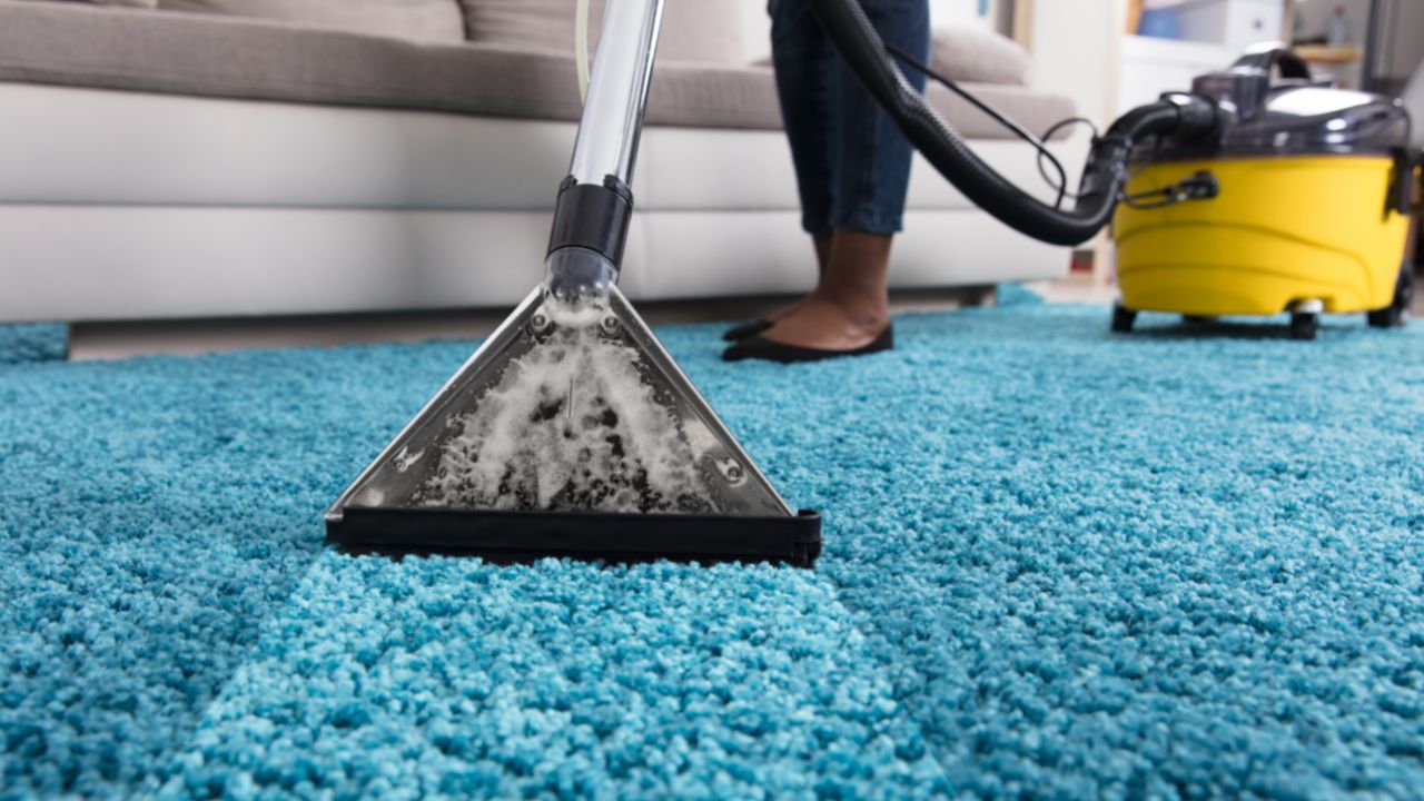 someone vacuuming a blue carpet