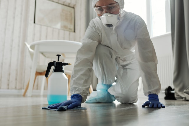 person in white hazmat suit cleaning white floor