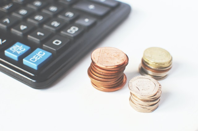 picture of calculator and three stacks of coins